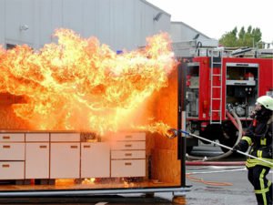 Firefighter battling a blaze to promote wildfire home hardening.